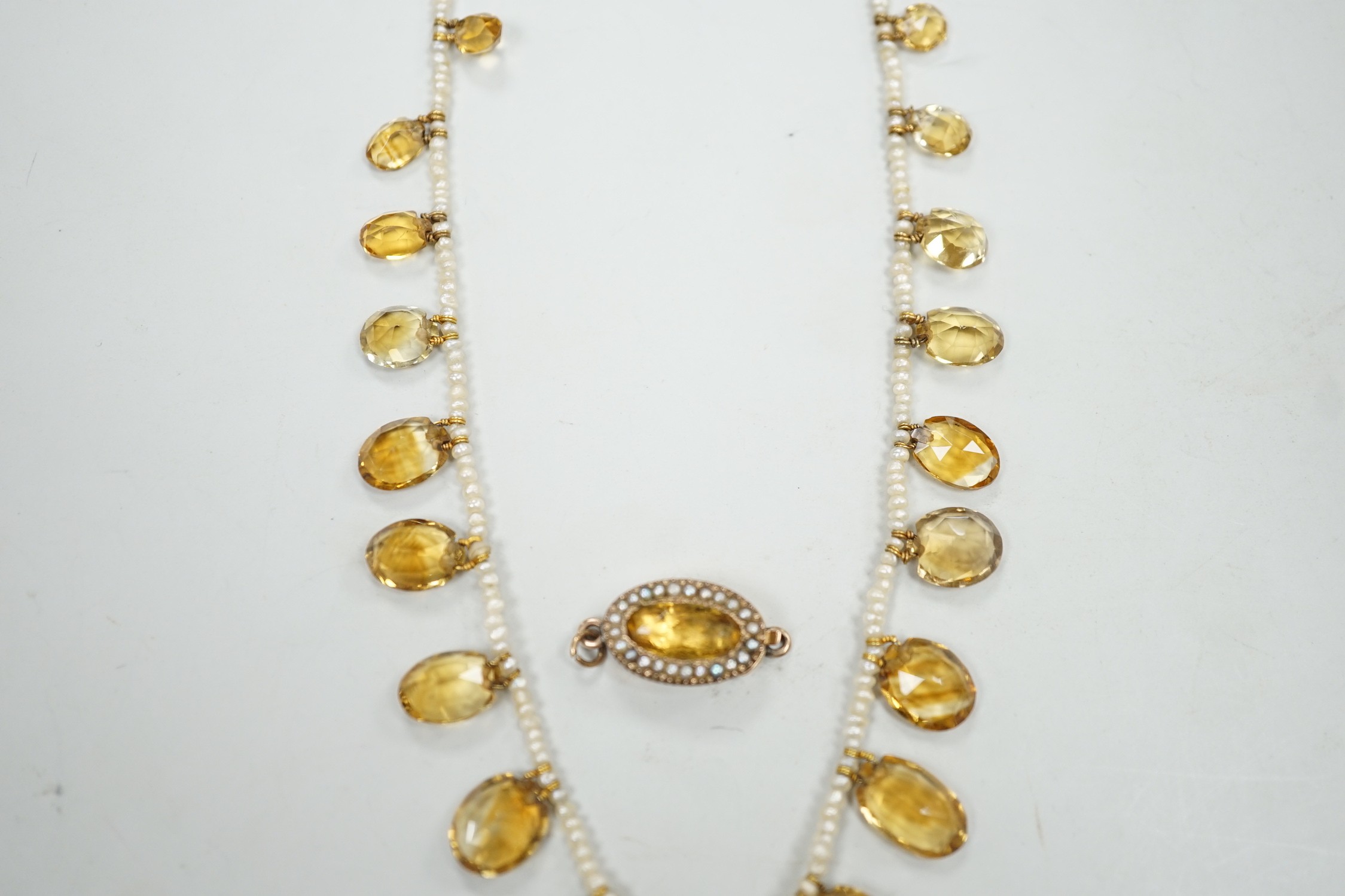 An Edwardian twenty one graduated oval cut citrine set seed pearl necklace (a.f) clasp loose, approx. 34cm.